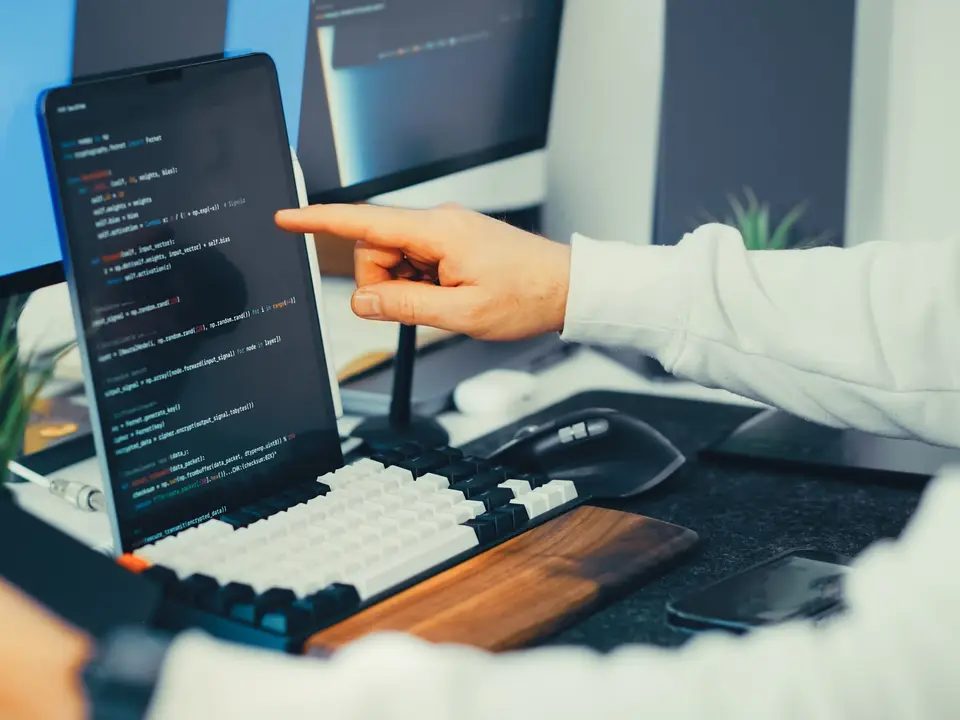 Programmer working on code with a laptop and monitor