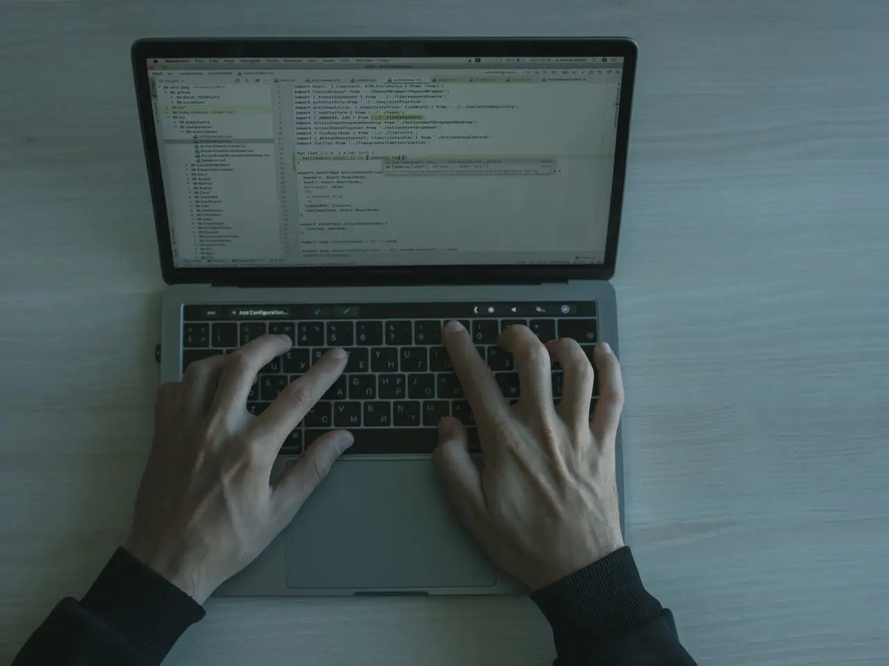 Developer writing code on a laptop in a dim office