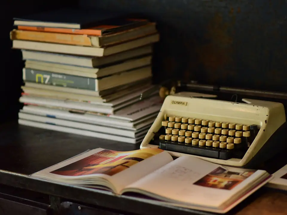 Typewriter beside a stack of worn books