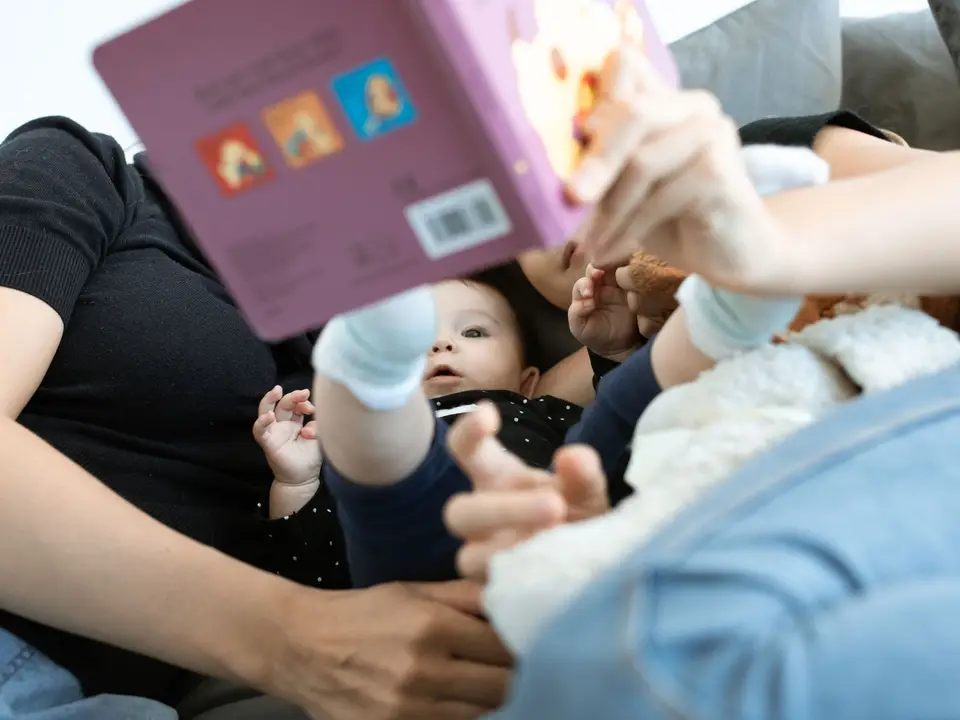 Parent reading with a toddler on a sofa