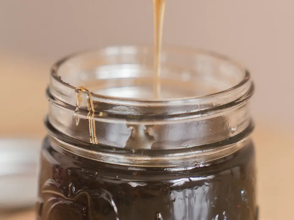 Golden honey being poured into glass jars