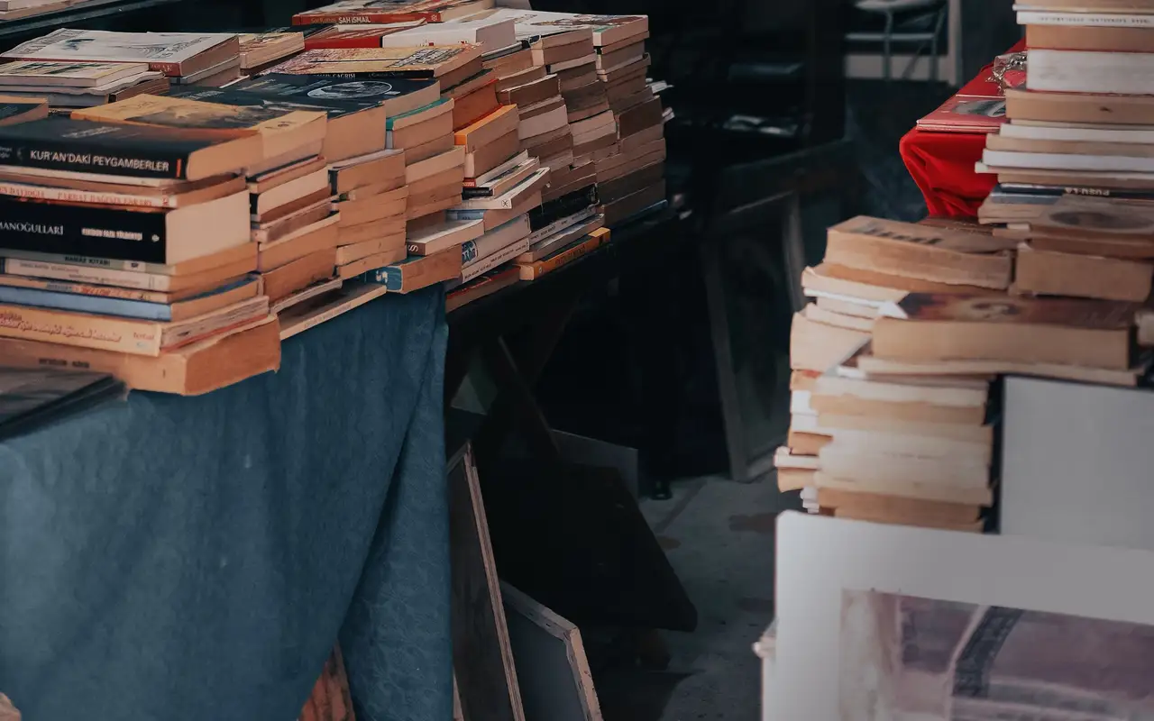 Hardcover books stacked beside a reading lamp