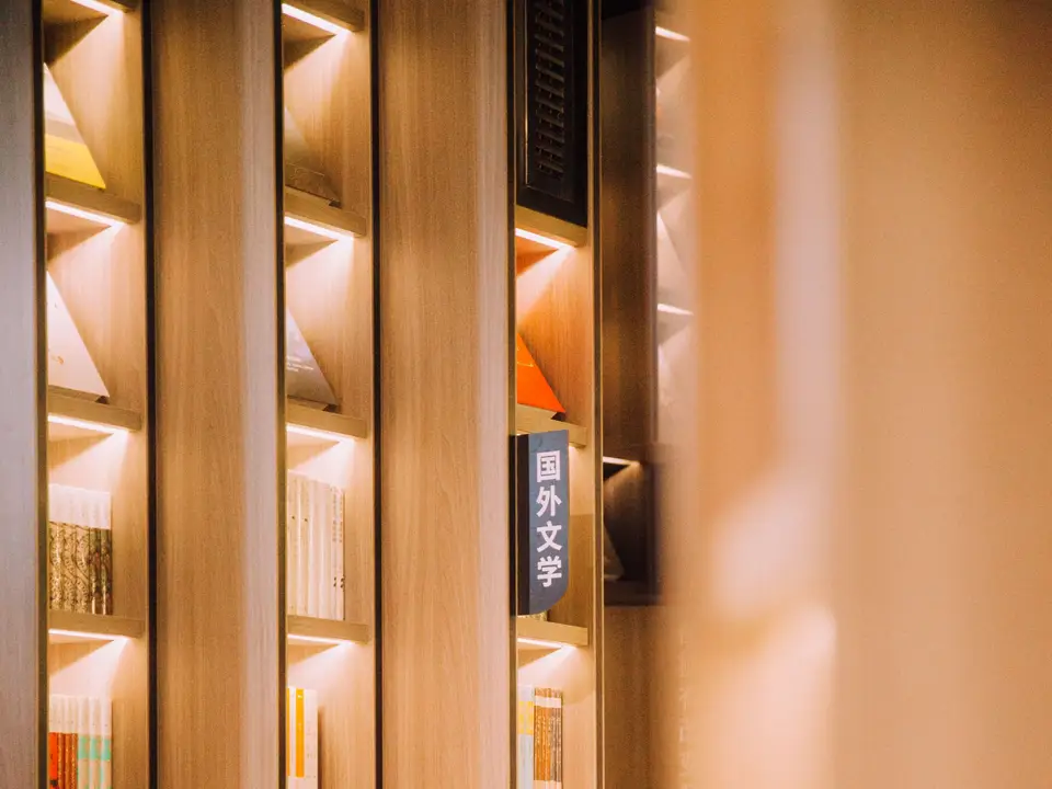 Barista serving coffee beside a shelf of novels