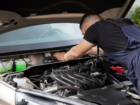 Technician wiping down a sedan in a service bay