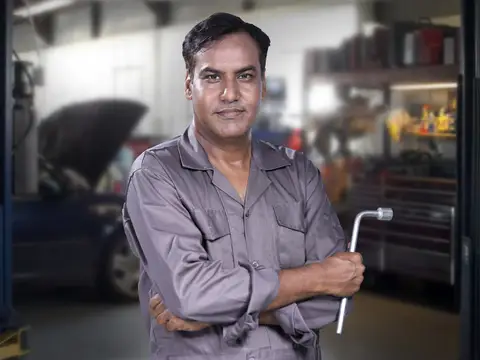 Technician working under a hood in a bay
