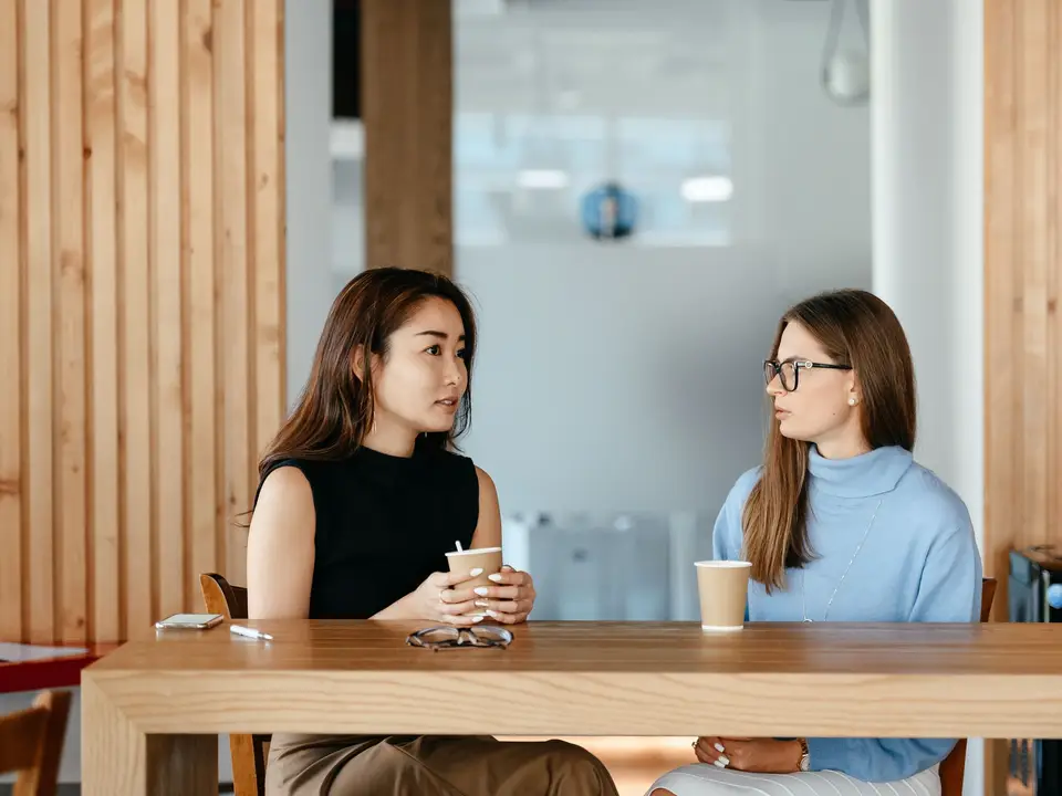 Two women talking over coffee at a table
