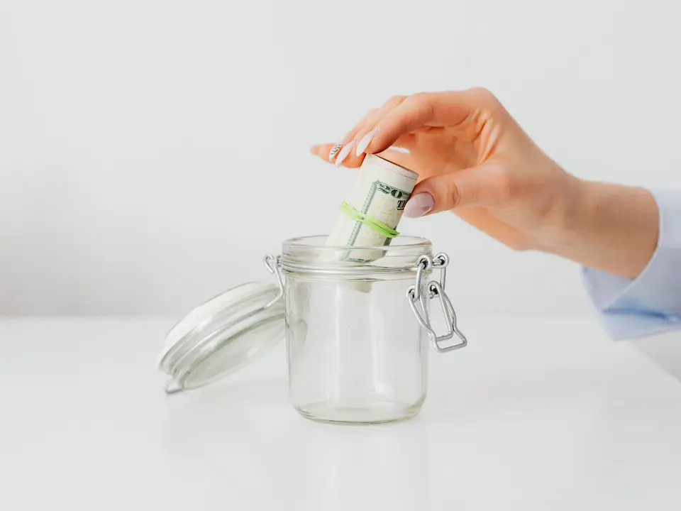 Donor dropping a cash gift into a donation jar