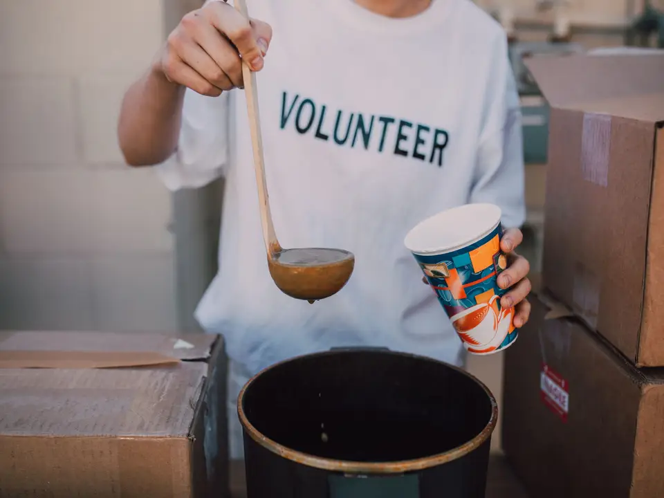 Volunteer ladling hot soup at a community meal service
