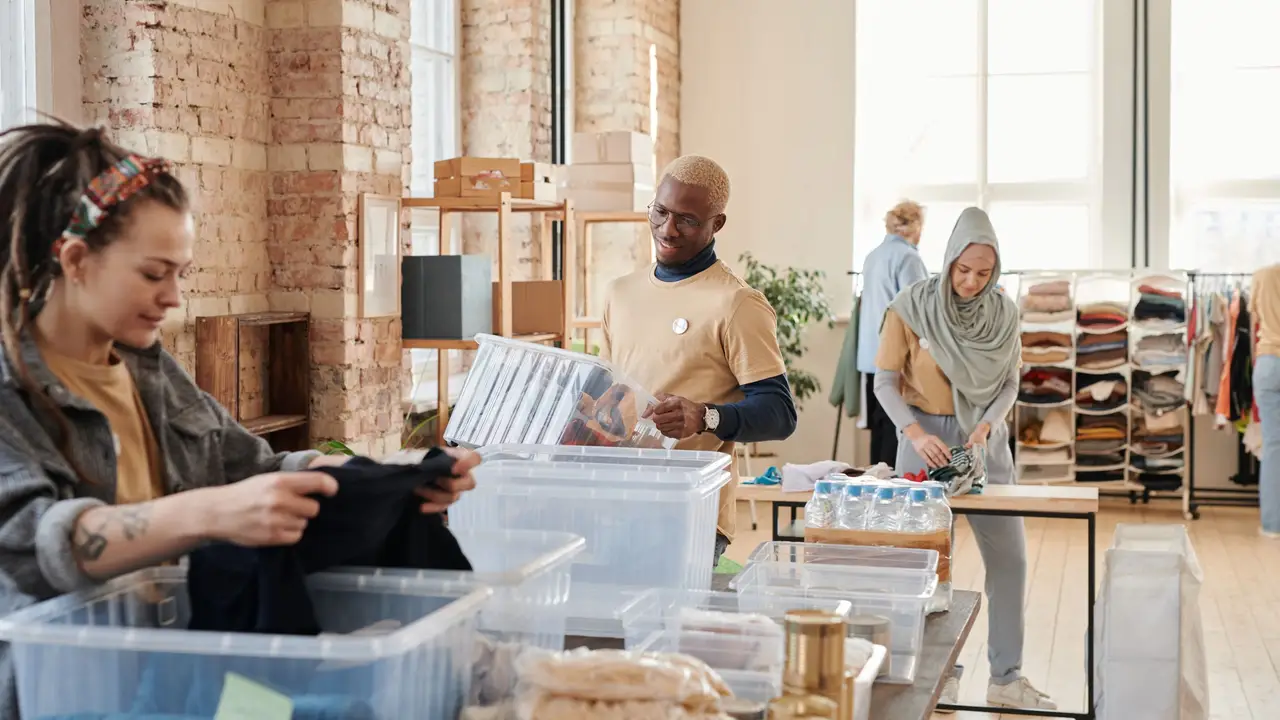 Group of diverse volunteers organizing donated clothing and supplies in a bright, airy warehouse