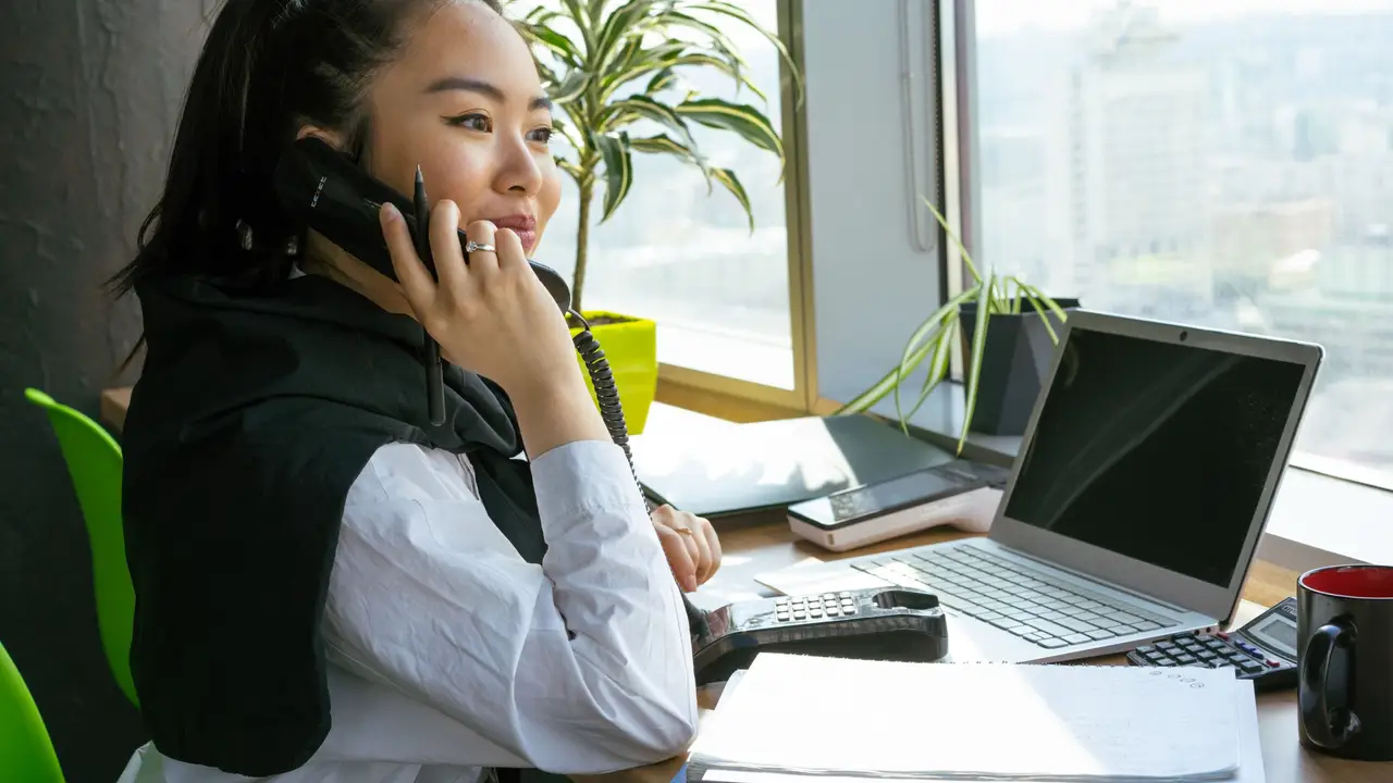 Coordinator on the phone confirming a landlord payment at her desk
