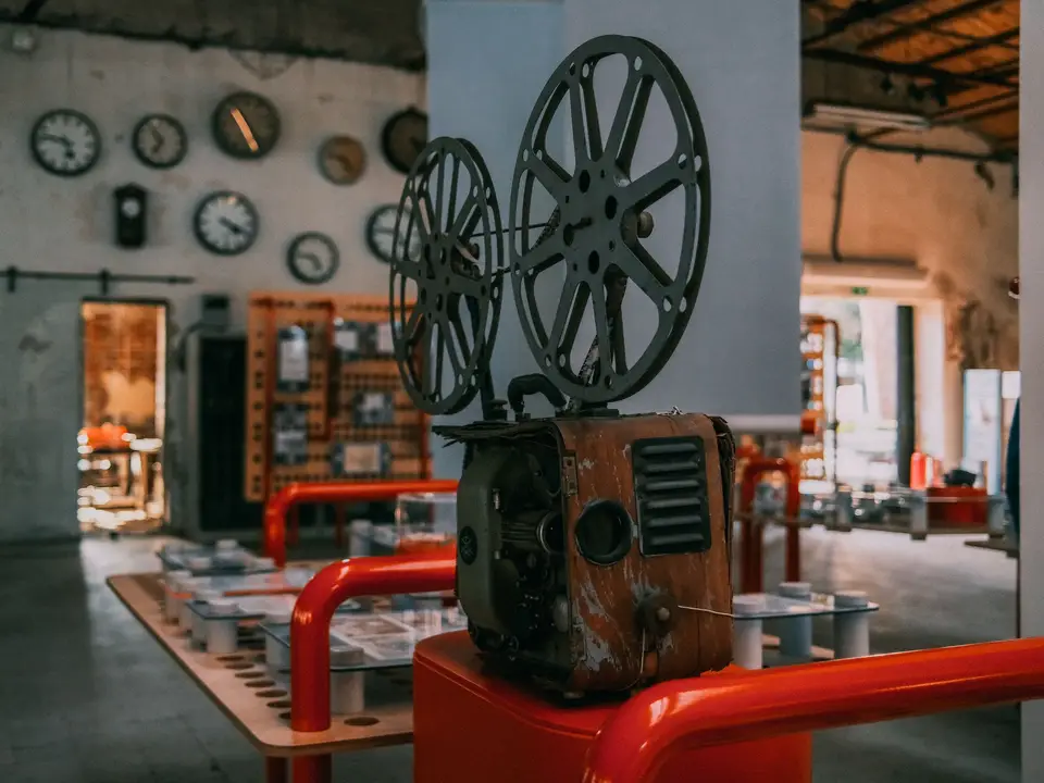 Vintage film projector on a red stand in a rustic interior