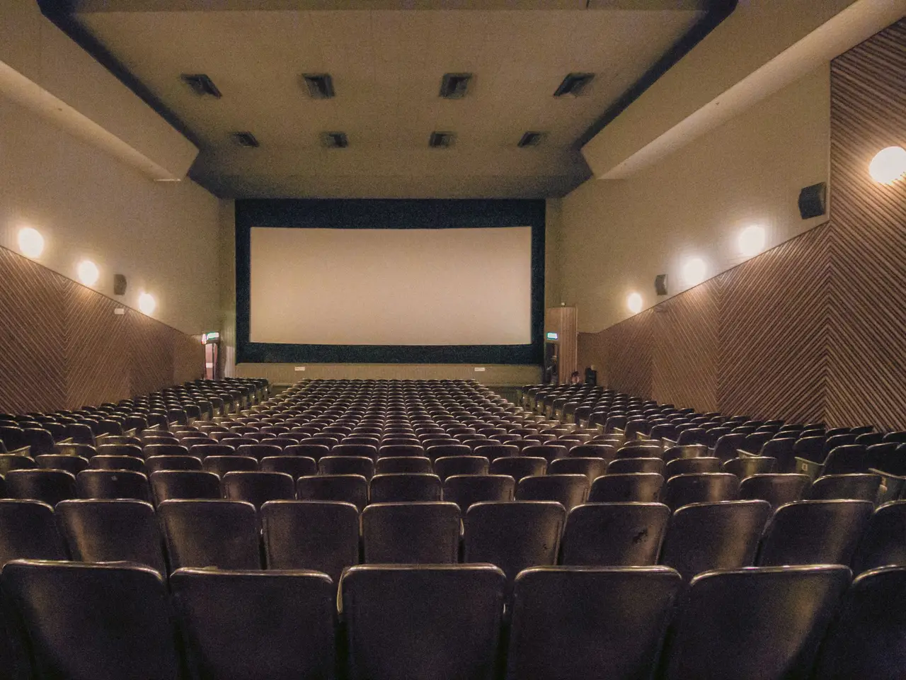 Cinema hall with rows of seats facing a large blank screen