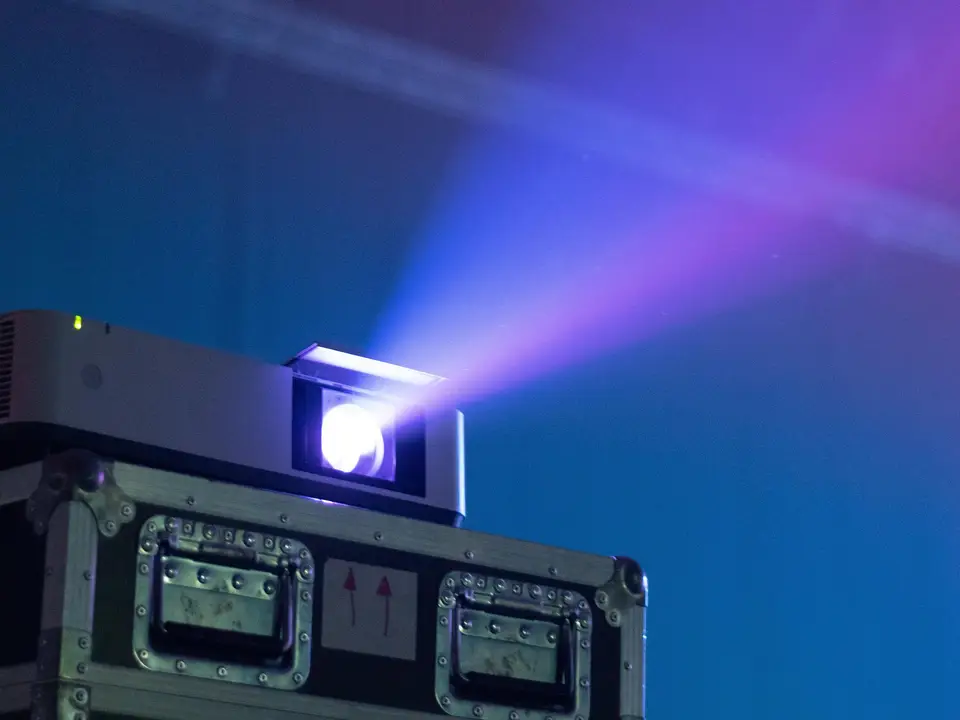 Projector lens throwing a beam of light in a dark room