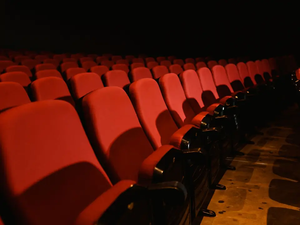 Rows of empty red cinema seats in a dim auditorium