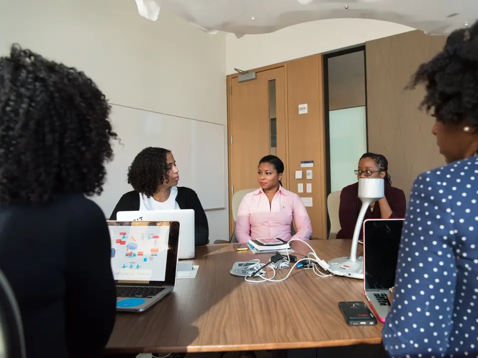 Team of adults collaborating in a meeting room with laptops