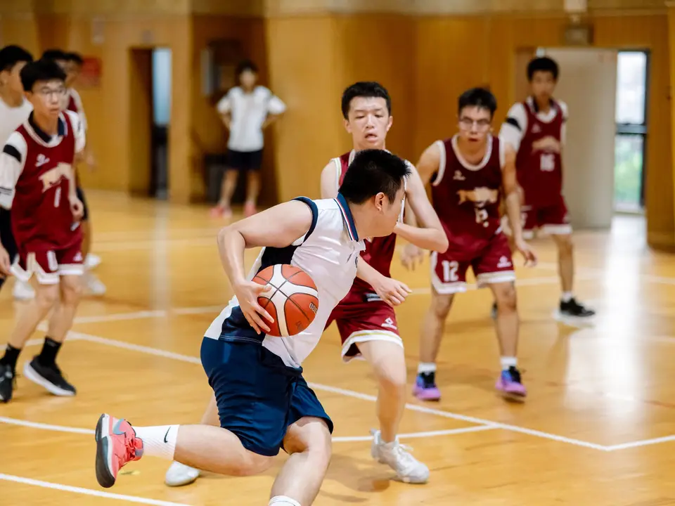 Teens playing a basketball game in a school gym