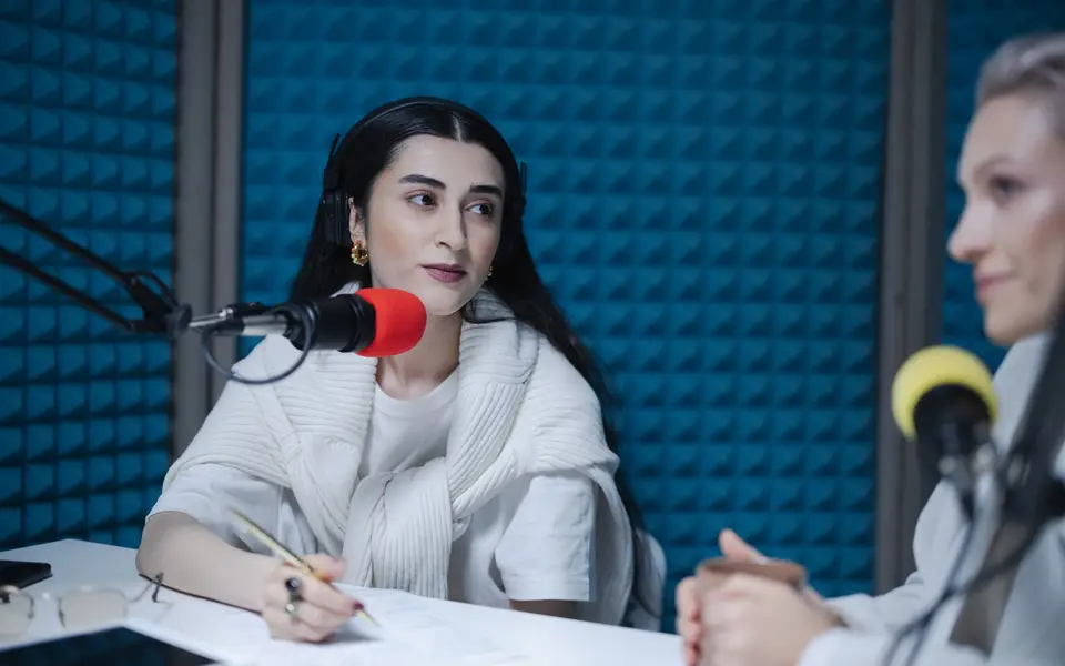 Two women engaged in a podcast recording with professional microphones