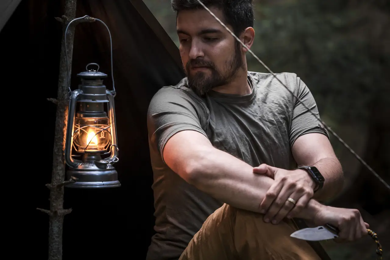 Glowing glass jar lantern on a table at dusk beside a window