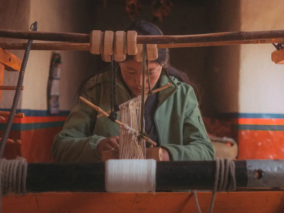 Artisan demonstrating weaving at a wooden loom