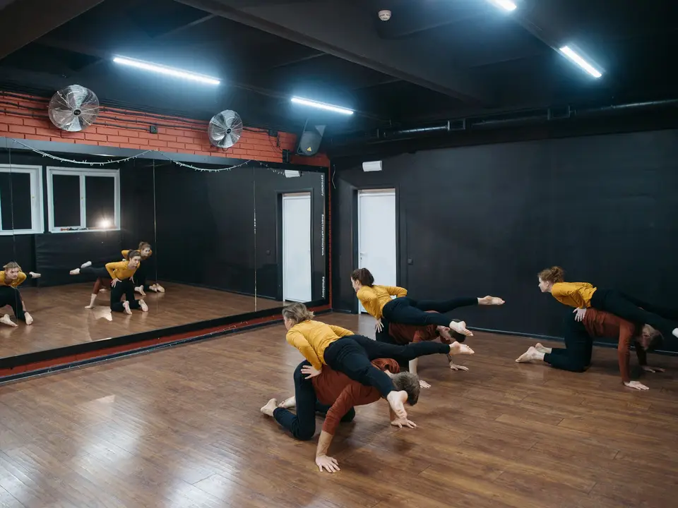 Group of dancers rehearsing contemporary choreography in a mirrored studio