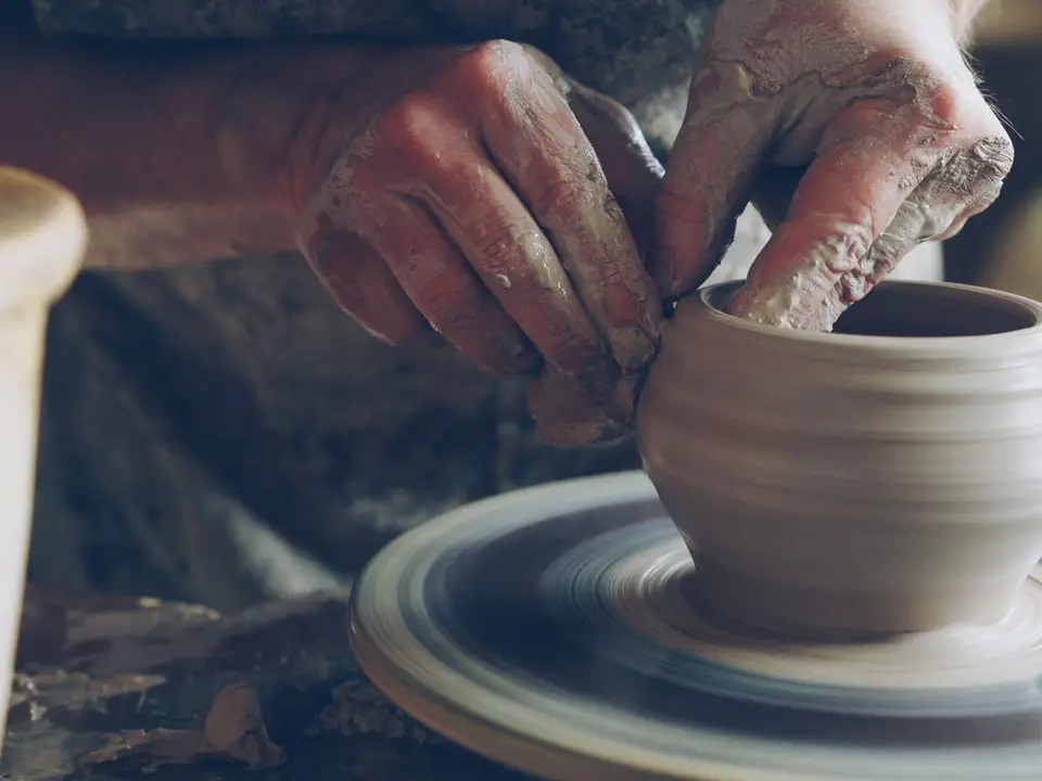 Artisan skillfully shapes clay on a spinning wheel, showcasing traditional pottery techniques