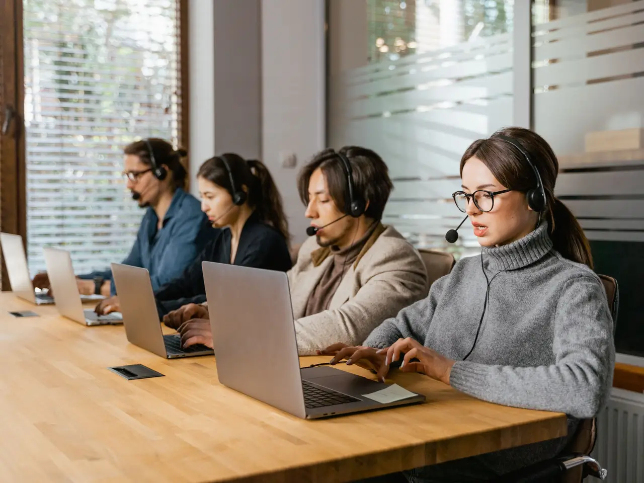 Call center team working at laptops with headsets