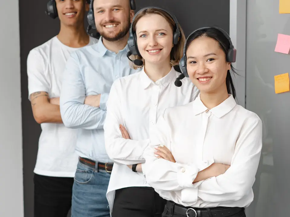 Friendly support team with headphones standing together in the office