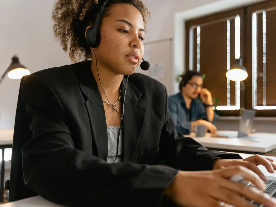 Support agent in headphones working on a laptop