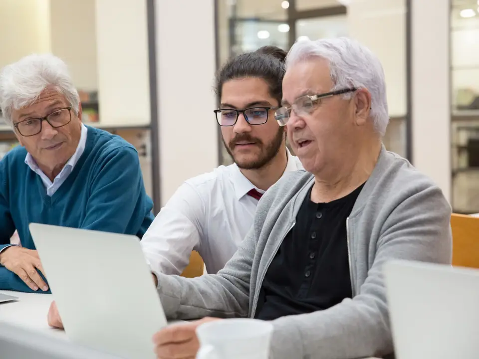 Three men learning technology together on laptops