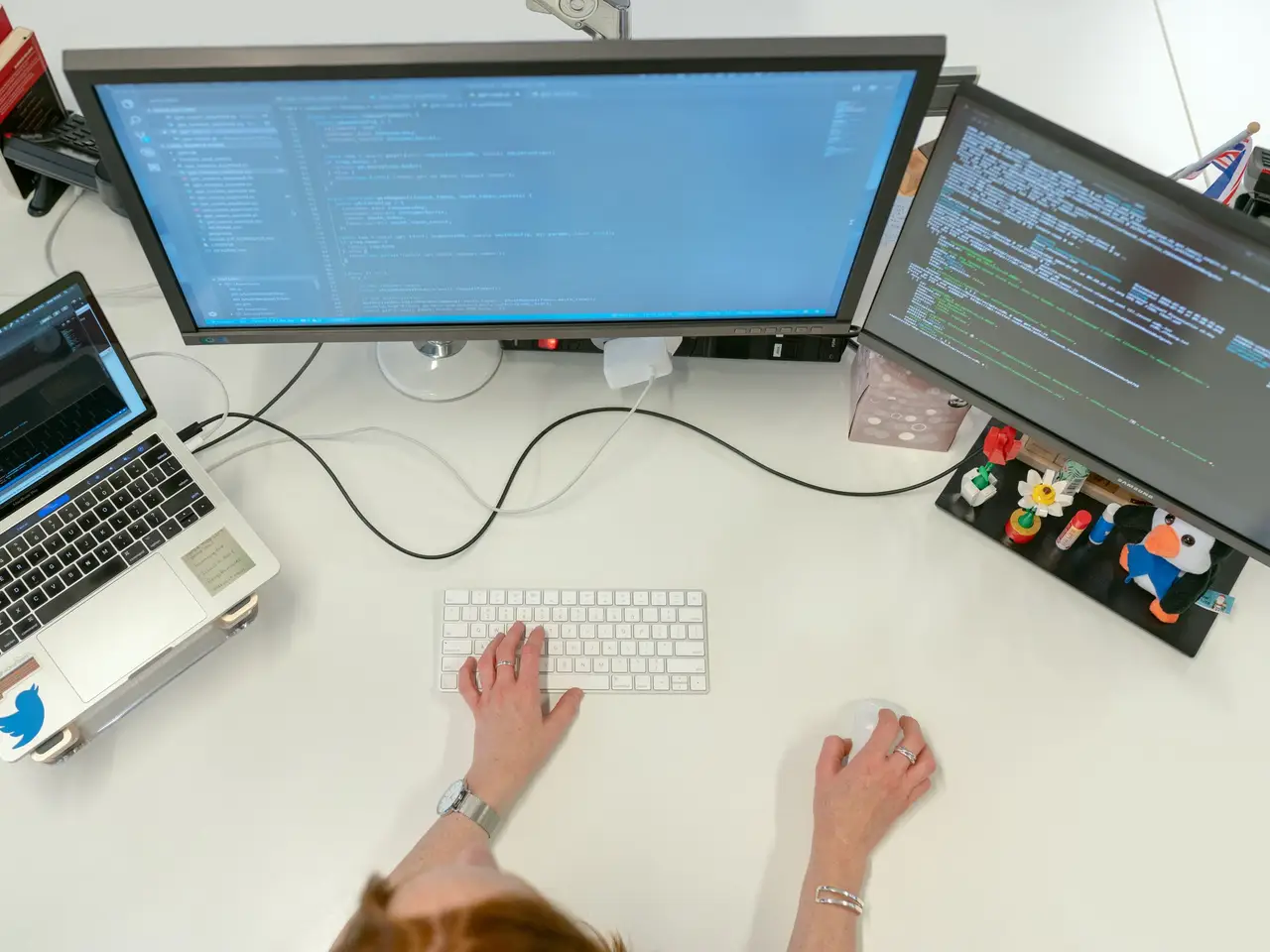 Software engineer coding on dual monitors and a laptop