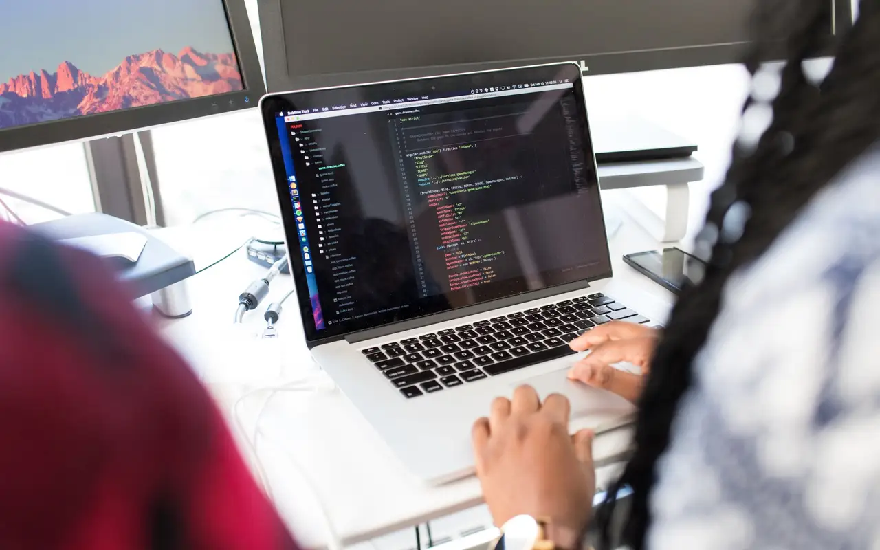 Icon designer refining vector paths on a widescreen monitor