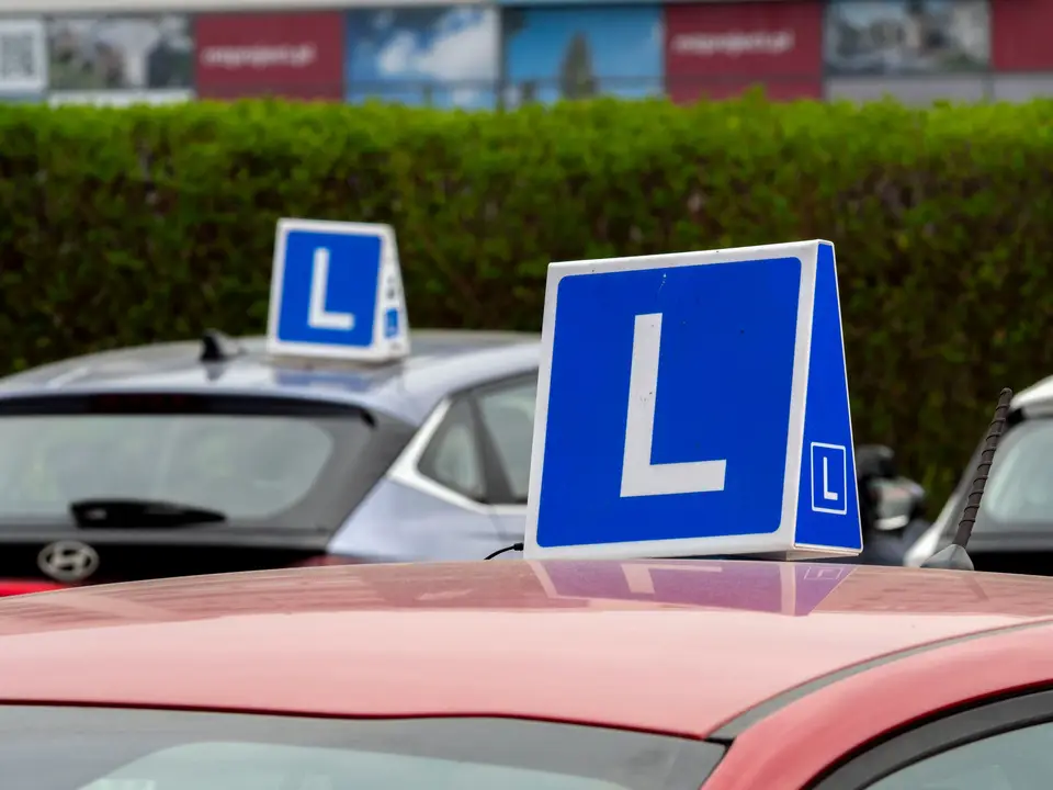 Cars with learner signs parked at a driving school training area
