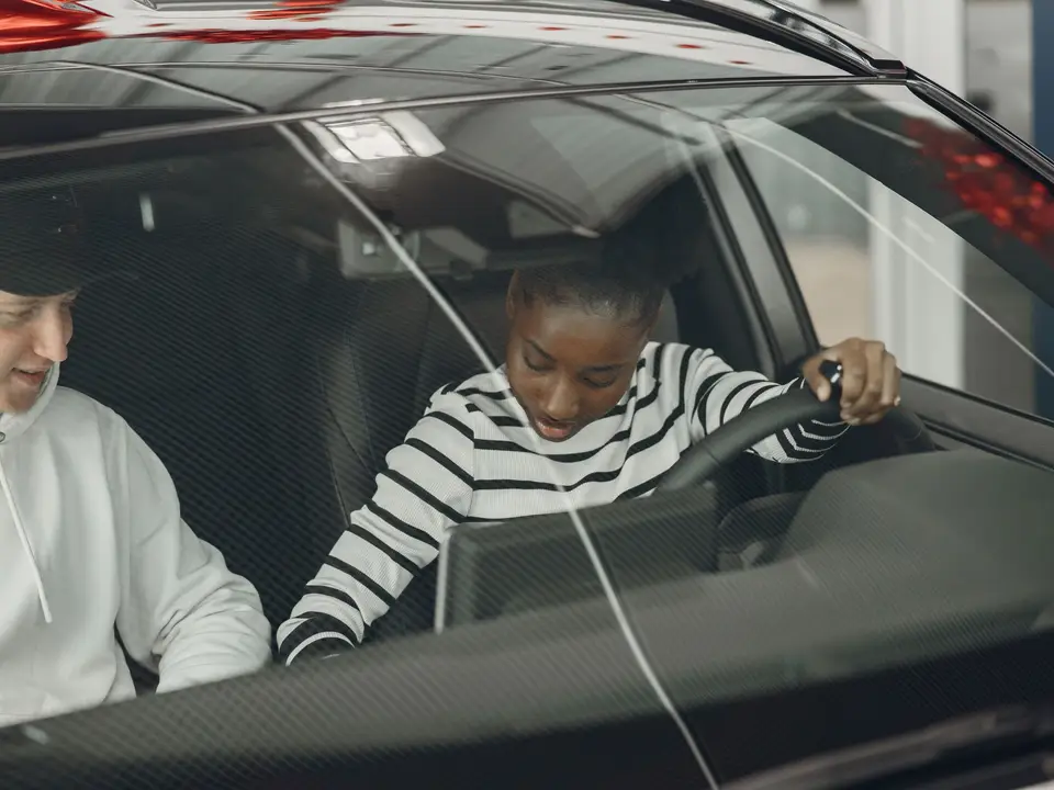 Two people sitting inside a car discussing driving