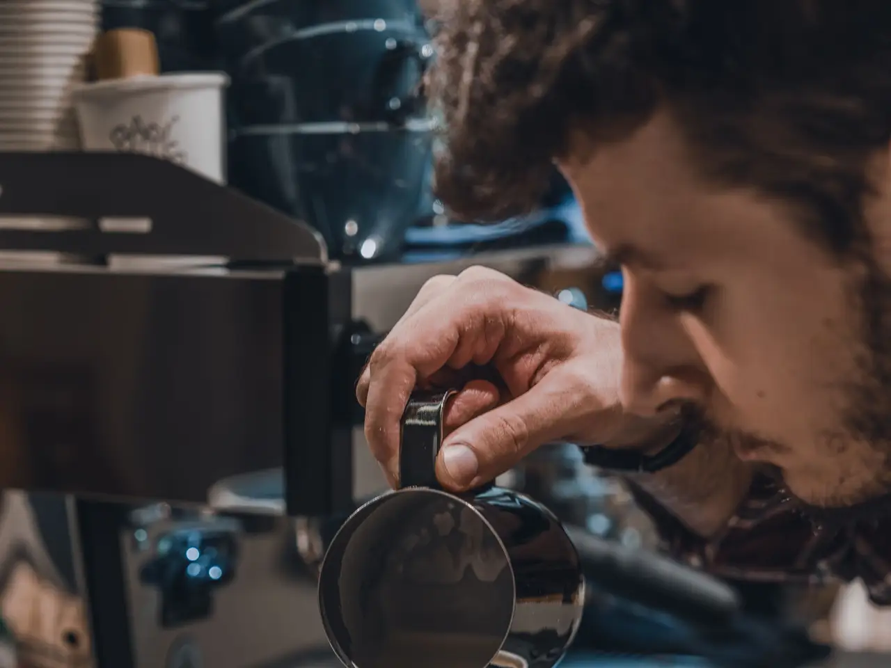 Barista pouring latte art in a ceramic cup