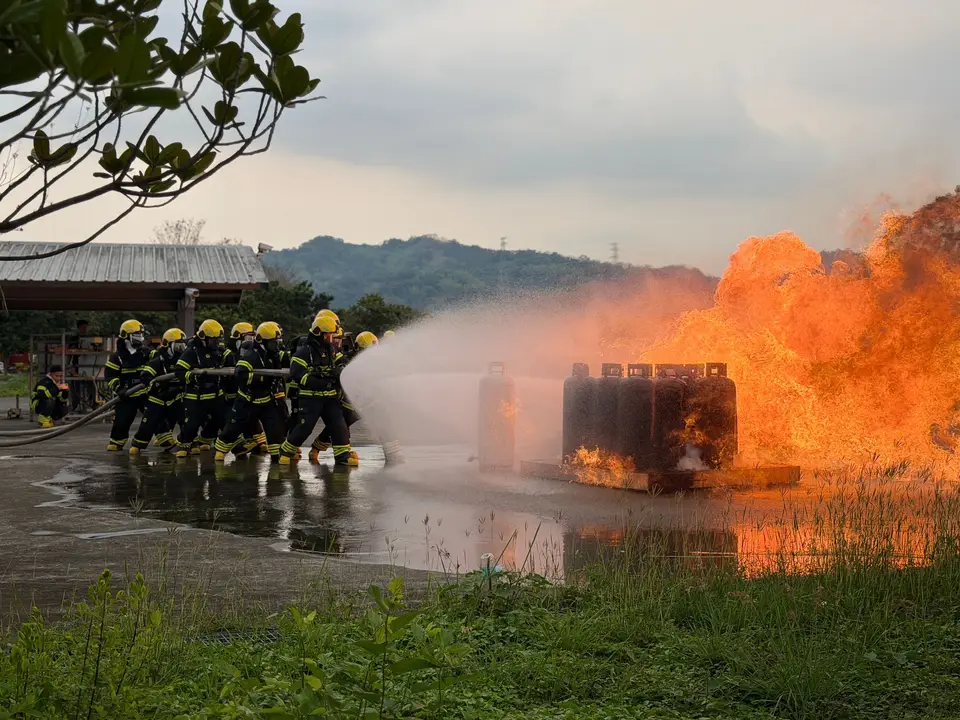 Firefighters in protective gear directing a high-pressure hose at a blaze