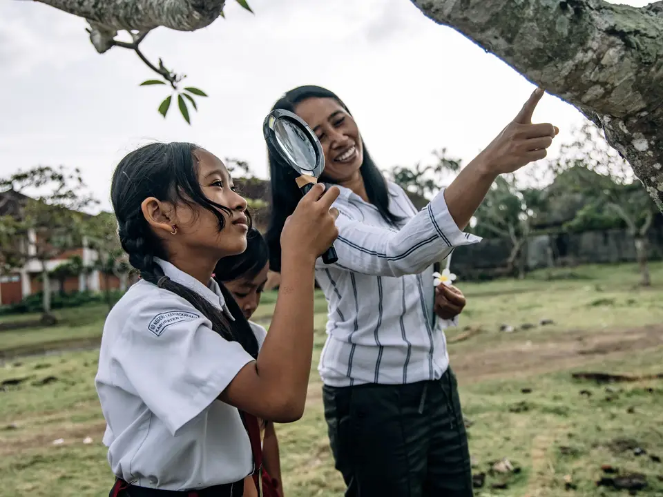 Students examining plants with a magnifying glass on a field trip
