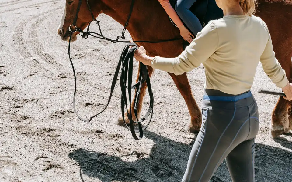 A woman teaching a young girl how to ride a horse