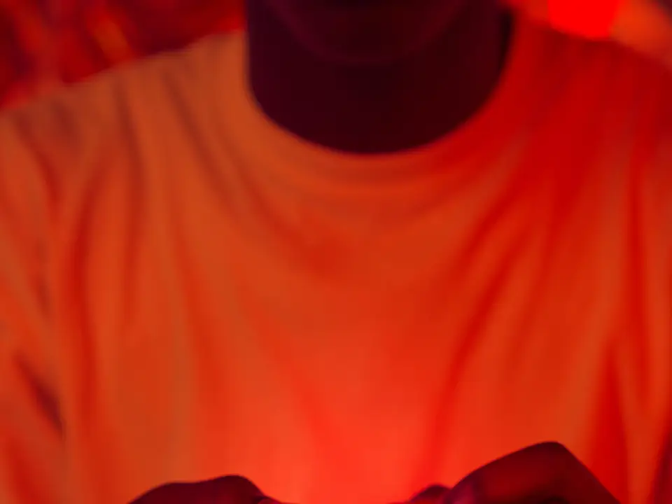 Hands holding a game controller in red ambient light