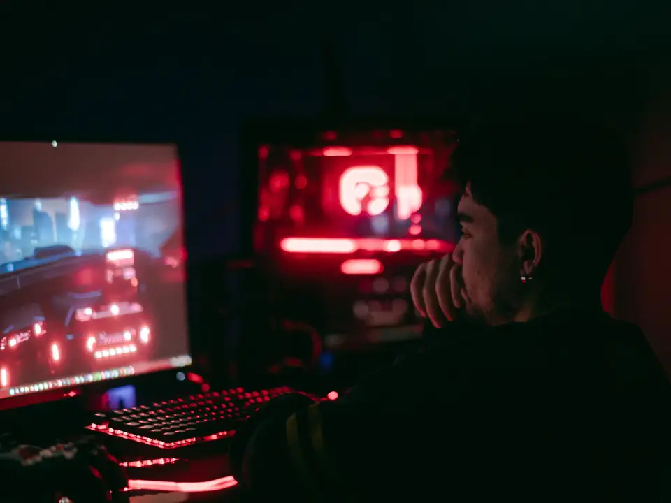 Player at a desktop with glowing red and blue lights in a dark room
