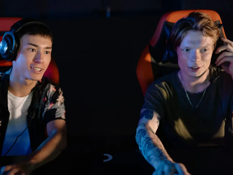 Two players with headsets focused on screens in a dim gaming room