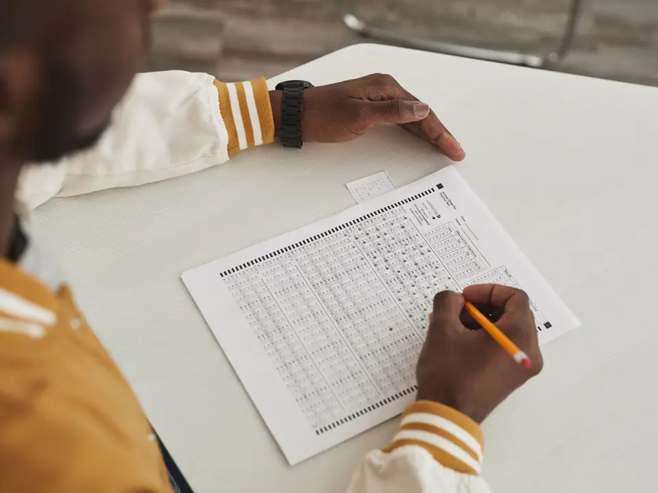 Focused student filling in a multiple choice sheet in a classroom