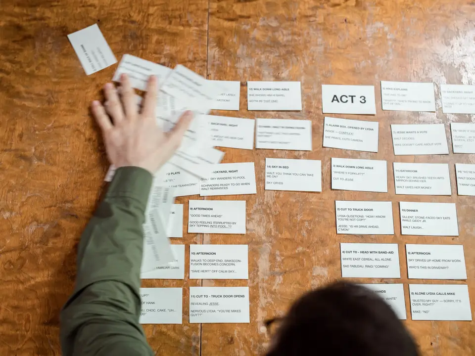 Storyboard cards labelled by act spread across a wooden table