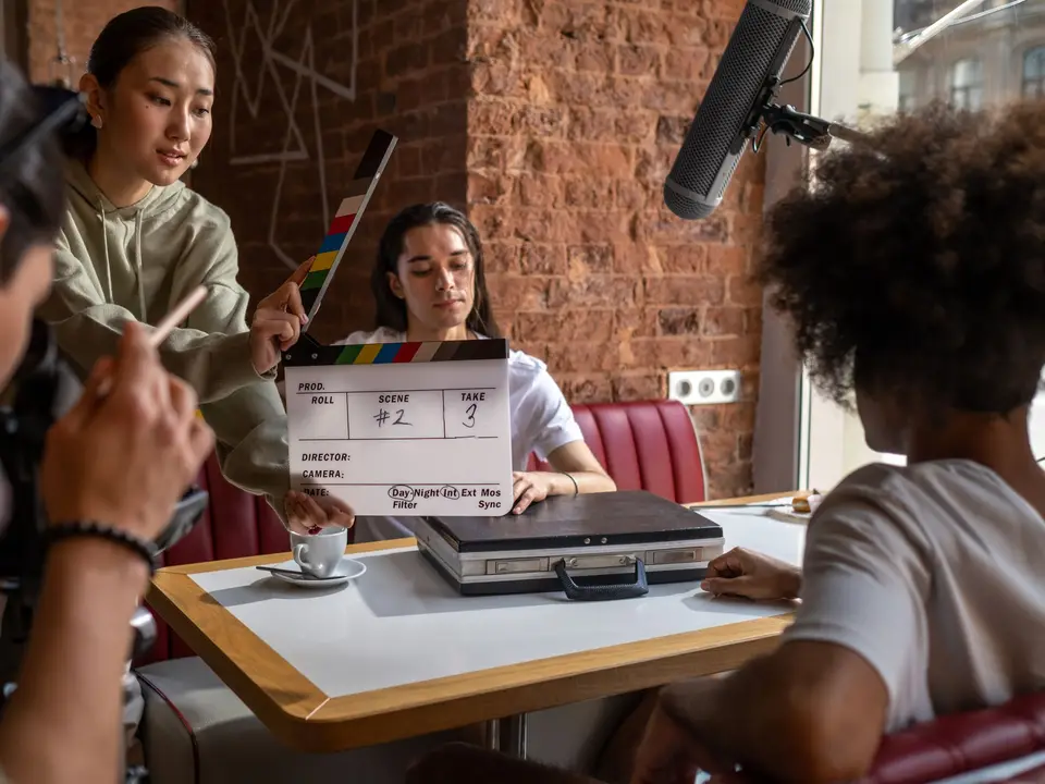 Cast and crew rehearsing a scene around a cafe table
