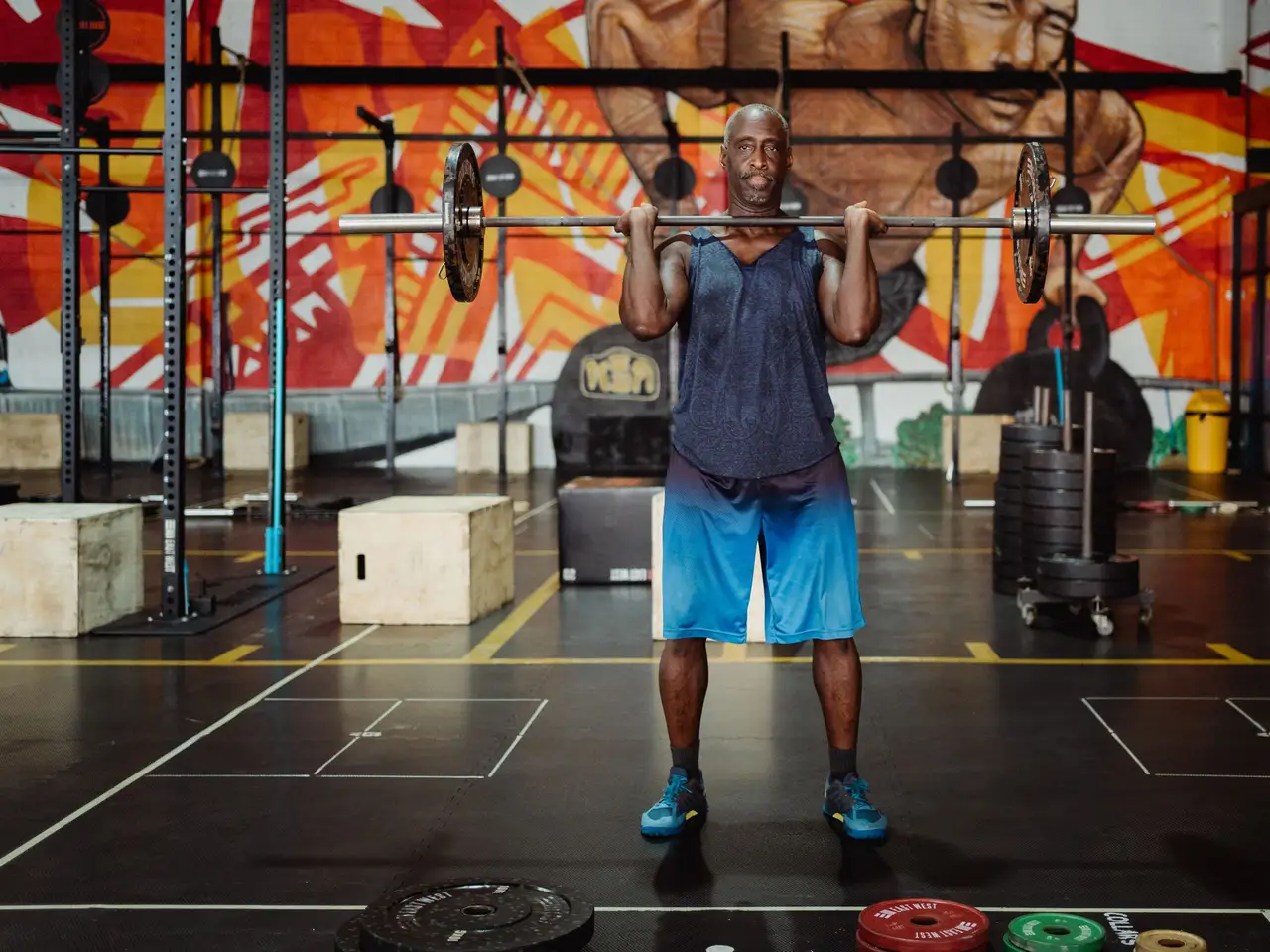 Muscular man lifting barbell in a colorful gym, exuding strength and fitness.