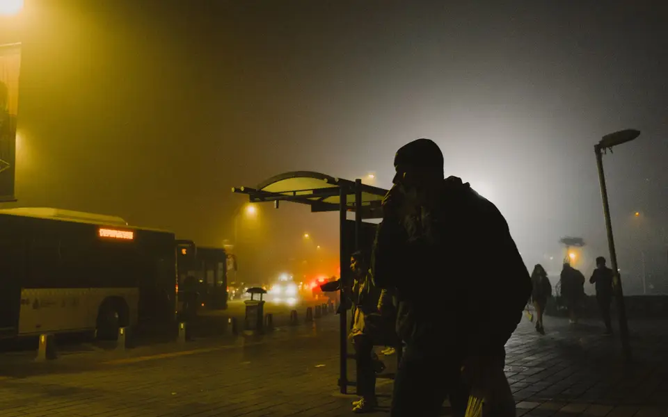 Foggy avenue with blurred bus headlights