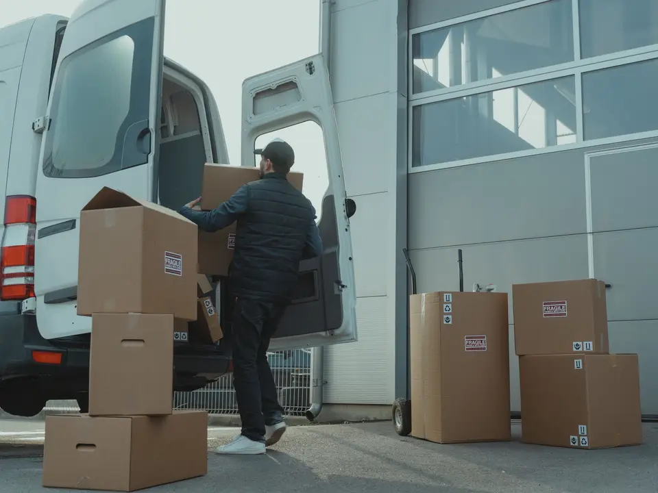 Driver loading produce boxes into a delivery van