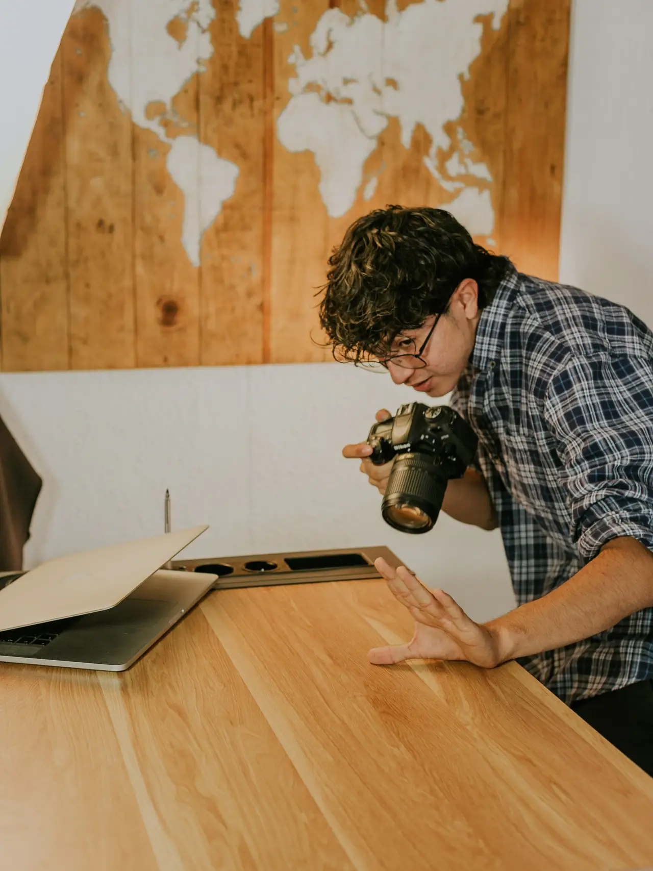 Man working at a wooden desk beneath a world map on the wall