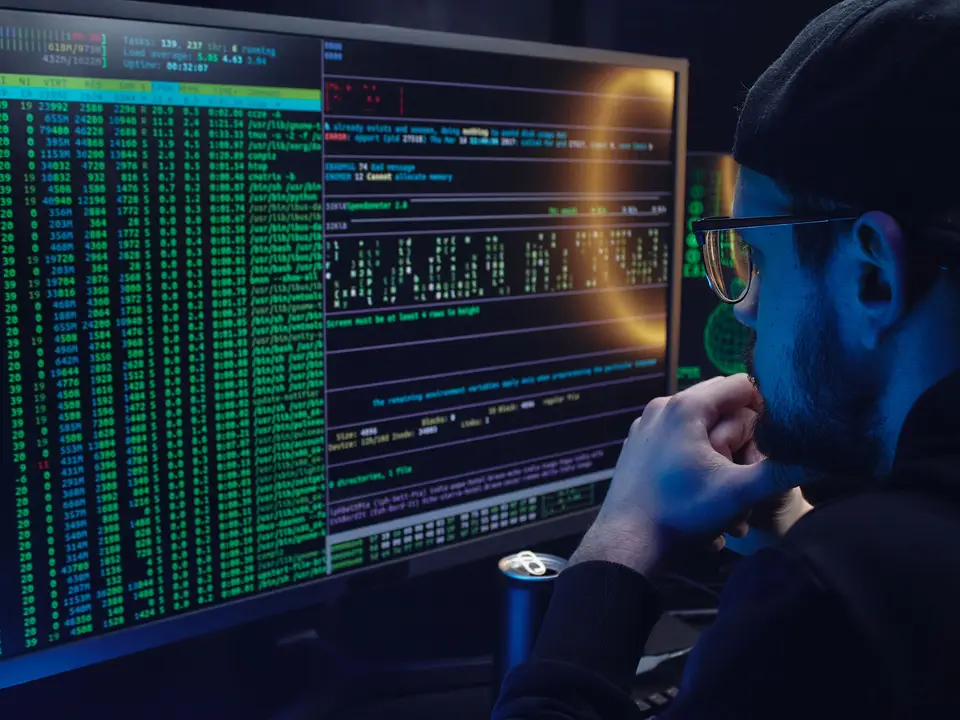Programmer viewed from behind looking at scrolling code on a large screen