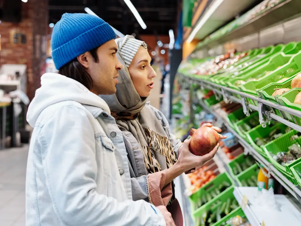 Shoppers selecting pomegranates in the produce section