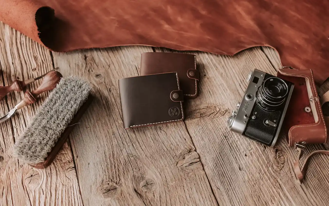 Leather wallets and a film camera on a workshop bench